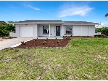 Charming single-story home with a well-maintained lawn, landscaped flower beds, and an attached single car garage at 7087 Spinnaker Blvd, Englewood, FL 34224