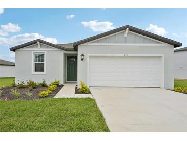 Charming single-Gathering home featuring a well-manicured lawn, green front door, and two-car garage at 145 Lazy Shore Dr, Nokomis, FL 34275