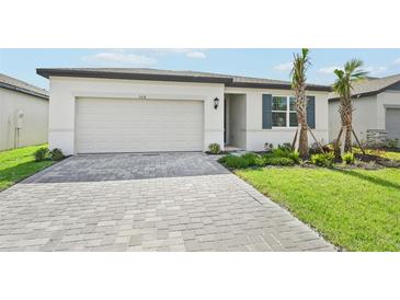 One-story home with light-colored siding, a two-car garage, and a landscaped lawn at 108 Runaway Field Ave, Nokomis, FL 34275