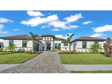 Beautiful single-story home featuring a brick driveway, manicured lawn, and decorative palm trees, all under a clear blue sky at 1529 Rio Vista Ter, Parrish, FL 34219