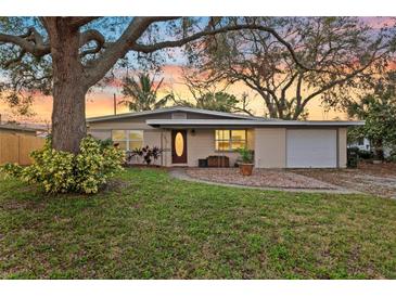 Charming single-story home featuring mature trees, a well-manicured lawn, and attached garage at 1023 Madison St, Largo, FL 33770