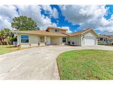 Tan house with a large yard, driveway, and two-car garage at 822 Diane Cir, Englewood, FL 34223