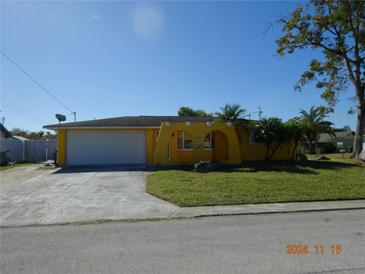 Yellow house with a single car garage and a neatly kept lawn at 8516 Bella Via, Hudson, FL 34667