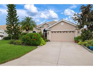 Tan house with a three-car garage and well-manicured landscaping at 6043 Anvil Ave, Sarasota, FL 34243
