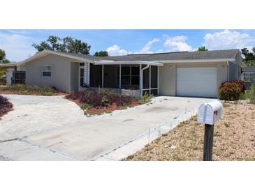 Ranch-style home with a carport and mature landscaping at 3314 Columbus Dr, Holiday, FL 34691