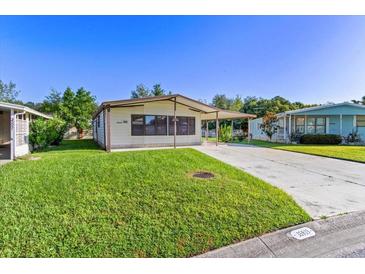 Single-wide manufactured home with carport and spacious lawn at 35935 Tanda Cir, Zephyrhills, FL 33541