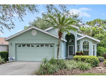 Single-story home with light green exterior, two car garage, and palm tree at 7319 Eleanor Cir, Sarasota, FL 34243