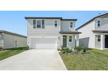 Two-story home showcasing a two car garage, neutral paint, a green front door and small front yard at 3825 Radiant Mountain Dr, Plant City, FL 33565