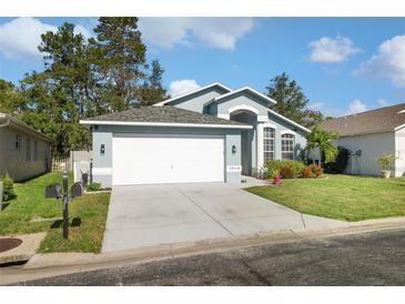 Beautiful blue home featuring an attached two-car garage and a well maintained front yard at 7940 Fashion Loop, New Port Richey, FL 34654