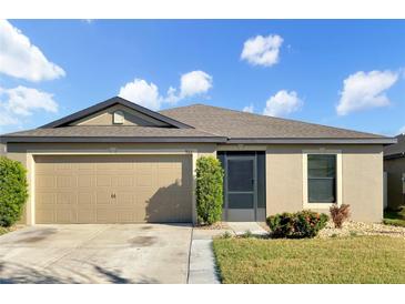 Tan one-story house with a two-car garage and landscaping at 922 Wynnmere Walk Ave, Ruskin, FL 33570