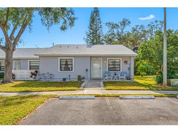 Cute Florida home with grey exterior, small front porch, and nicely landscaped lawn at 1125 Somerset S Cir, Dunedin, FL 34698