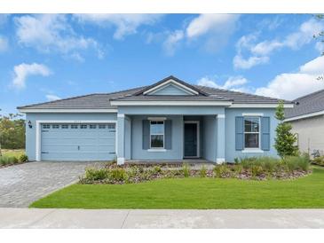 Charming one-story home featuring a blue exterior, well-manicured lawn, and a two-car garage at 2515 Wise River Lane, Zephyrhills, FL 33539