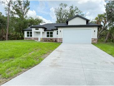 Charming single-story home featuring a manicured lawn and a spacious two-car garage at 1074 Kacerik St, North Port, FL 34288