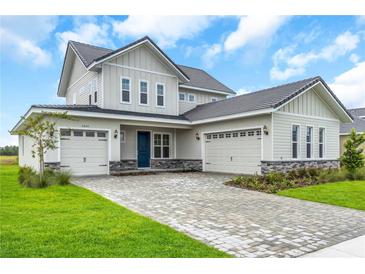Charming two-story home featuring a three-car garage, stone accents, and well-manicured landscaping at 2626 Wise River Lane, Zephyrhills, FL 33539