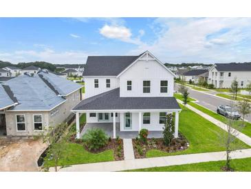 Two-story white farmhouse with a gray roof and landscaped yard at 3611 Lajuana Blvd, Wesley Chapel, FL 33543