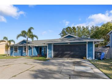 Ranch-style home with a two-car garage and palm trees at 4727 Windflower Cir, Tampa, FL 33624