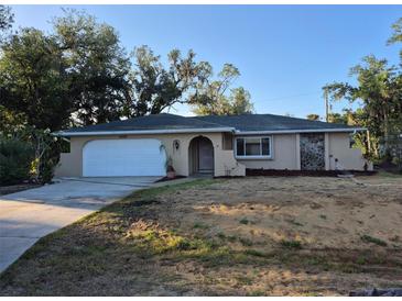 Charming one-story home with a front lawn, a white garage door and an arched front door at 21300 Washburn Ave, Port Charlotte, FL 33952