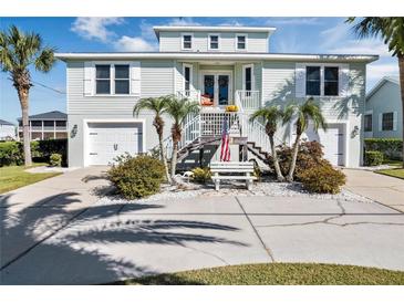 Two-story light green house with a large driveway, landscaping, and palm trees at 4049 Cobia Dr, Hernando Beach, FL 34607