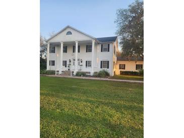 Two-story house with white columns and a lush green lawn at 15625 State Road 62 St, Parrish, FL 34219