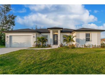 White single-story house with a gray roof, two-car garage, and landscaping at 10625 Ayear Rd, Port Charlotte, FL 33981