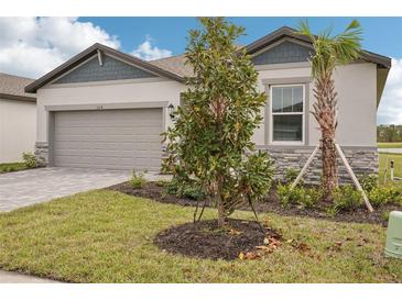 New home with landscaping, paver driveway, and inviting front entrance at 104 Runaway Field Ave, Nokomis, FL 34275
