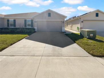 Two-car garage and well-maintained front yard with a long driveway at 17827 Turning Leaf Cir, Land O Lakes, FL 34638