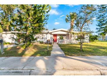 White house with red door, picket fence, and mature landscaping at 2695 S East Ave, Sarasota, FL 34239