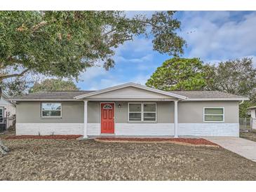 Updated one-story home with gray siding, red door, and landscaping at 11615 Meadow Dr, Port Richey, FL 34668