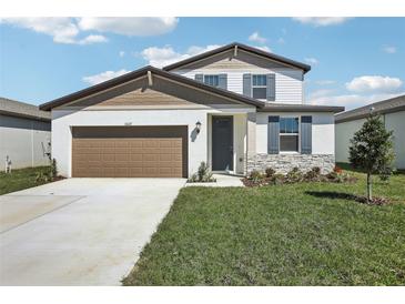 Charming two-story home featuring stone accents, gray shutters, a brown garage door, and a well-manicured lawn at 31637 Malbec Dr, Brooksville, FL 34602