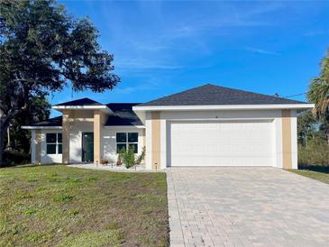 Charming single-story home featuring a well-manicured lawn, brick paved driveway, and attached two-car garage at 37 Warrington Blvd, Port Charlotte, FL 33954