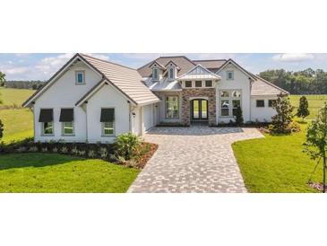 Beautiful home featuring stone accents, a paved driveway, and a well manicured lawn at 14036 Prairie Hill Rd, Dade City, FL 33525