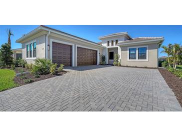 Elegant home with a wide driveway, a two-car garage, beautiful landscaping, and a neutral-colored exterior at 4621 Mondrian Ct, Sarasota, FL 34240