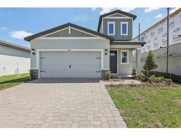 Charming two-story home features a gray exterior, a brick driveway, and a well-manicured lawn at 1852 Brekey Way, Zephyrhills, FL 33541