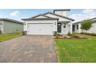 Charming single-Gathering home with a brick driveway, two-car garage, and professionally landscaped front yard at 1868 Brekey Way, Zephyrhills, FL 33541