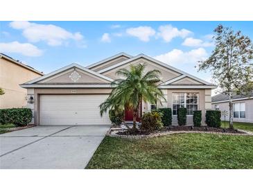 Charming single-story home with well-manicured lawn and a two-car garage, nestled under a sunny sky at 30350 Grymes Dr, Wesley Chapel, FL 33545