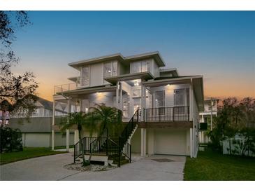 Stunning multilevel modern home with balconies, lush landscaping, and ample parking at 606 Indiana Ave, Crystal Beach, FL 34681