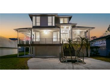 Stunning two-story home with a spacious porch and modern design, showcasing beautiful curb appeal at 606 Indiana Ave, Crystal Beach, FL 34681