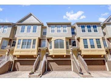 Townhome exterior featuring a three-story facade, drive-in garages, and private entrances at 4324 Spinnaker Cove Ln, Tampa, FL 33615