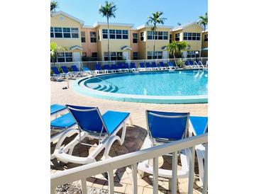 Community pool with blue lounge chairs and nearby condominium buildings on a bright, sunny day at 19417 Gulf Blvd # B209, Indian Rocks Beach, FL 33785