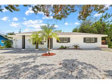 Charming single-story home with white exterior, dark trim, palm trees, and modern landscaping at 1154 64Th S Ave, St Petersburg, FL 33705