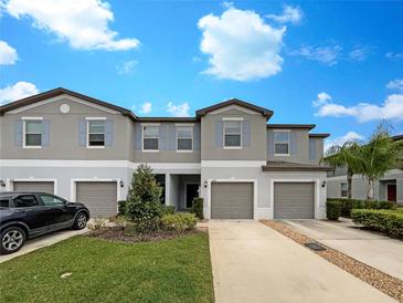 Townhouse exterior features a well-manicured lawn, concrete driveway, attached garages, and beautiful blue shutters at 1526 Cassius St, Lutz, FL 33549