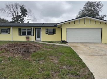 Charming yellow home with a well-manicured lawn and an attached garage, ready for new owners at 1998 Cove Dr, Largo, FL 33774