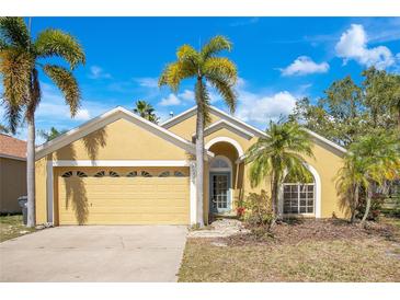 Charming single-story home with a two-car garage and well-maintained landscaping featuring tropical palm trees at 7622 Hampshire Garden Pl, Apollo Beach, FL 33572