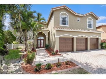 Charming two-story home with a three-car garage, beautiful landscaping, and a tile roof at 5802 Hatteras Palm Way, Tampa, FL 33615