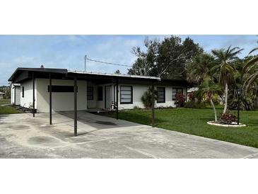 Charming single-story home with a carport and well-maintained front yard and lush tropical landscaping at 201 Ravenna N St, Nokomis, FL 34275