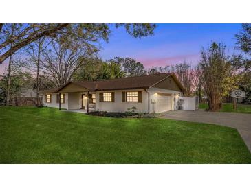 Charming single-story home featuring a well-manicured lawn, attached garage, and a basketball hoop on the driveway at 32589 Greenwood Loop, Wesley Chapel, FL 33545