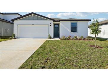 Exterior showcasing a white one-story house with a green lawn, driveway, and blue sky at 31632 Malbec Dr, Brooksville, FL 34602