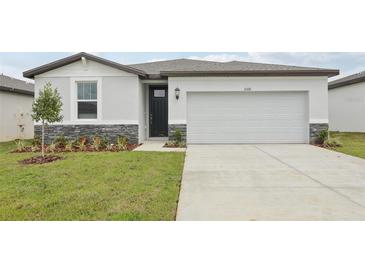 Charming single-story home with a gray stone accent, well-maintained lawn, and a two-car garage at 31681 Wild Grape Ln, Brooksville, FL 34602