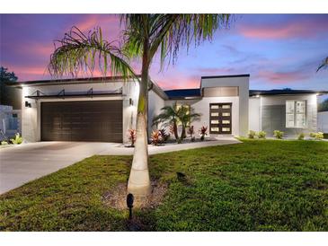 Charming home featuring well-manicured lawn, fresh landscaping and a modern black garage door at 24470 Kingsway Cir, Punta Gorda, FL 33983