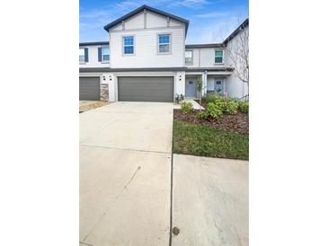 Charming two-story townhouse featuring a one-car garage, light gray facade and manicured landscaping at 32100 Pop Ash Pl, San Antonio, FL 33576